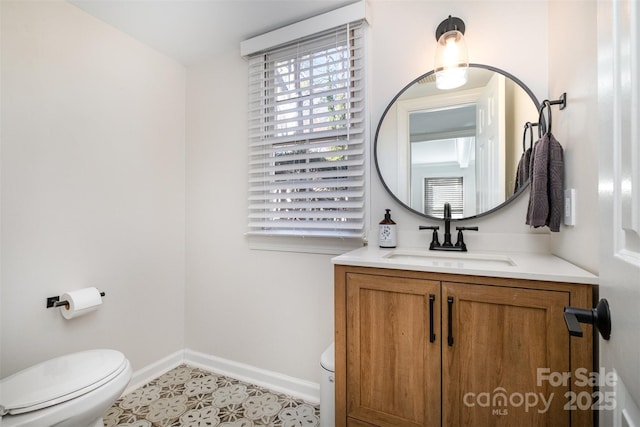 half bathroom with vanity, toilet, baseboards, and tile patterned flooring