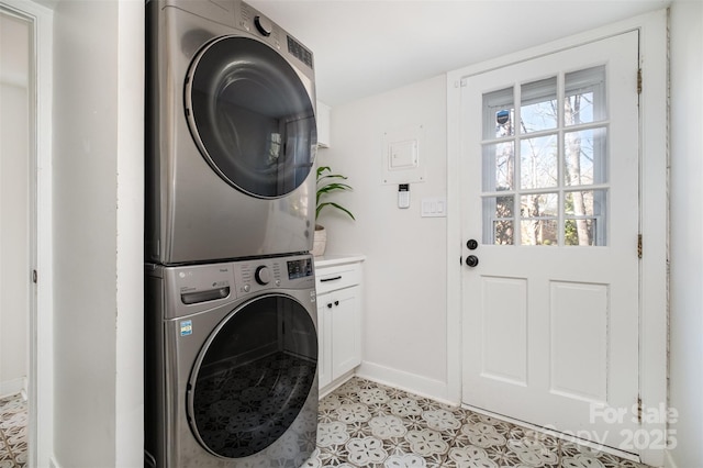 laundry room with cabinet space, stacked washer and clothes dryer, and baseboards