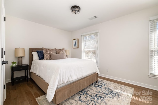 bedroom featuring dark wood-type flooring, multiple windows, baseboards, and visible vents