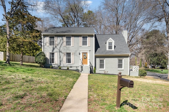 view of front facade featuring a front yard, fence, roof with shingles, and a chimney