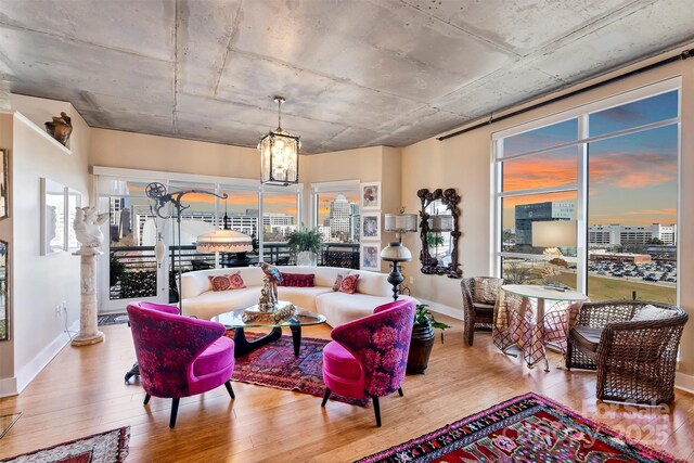 living area with baseboards, decorative columns, a chandelier, and wood finished floors