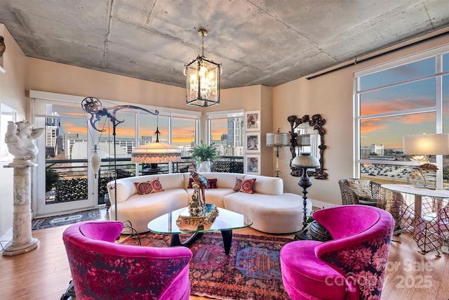 living room featuring wood-type flooring, a healthy amount of sunlight, a notable chandelier, and decorative columns