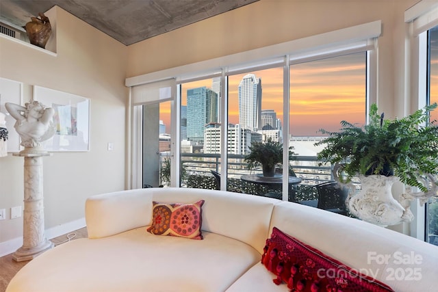 bedroom with a city view, decorative columns, baseboards, and wood finished floors