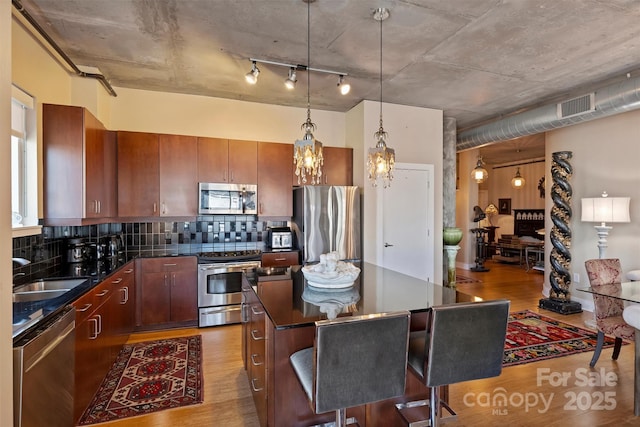 kitchen with dark countertops, visible vents, appliances with stainless steel finishes, light wood-style floors, and a sink