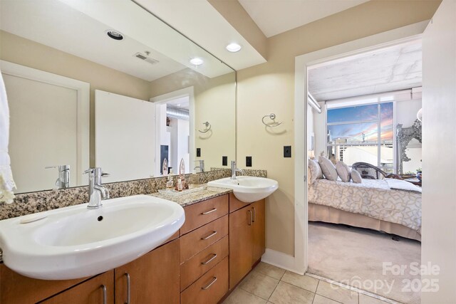 ensuite bathroom with ensuite bathroom, double vanity, a sink, and visible vents