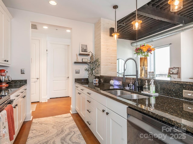 kitchen featuring white cabinets, dark stone counters, stainless steel appliances, and a sink