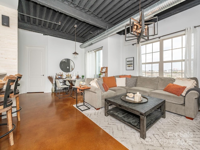 living area featuring a towering ceiling, plenty of natural light, concrete floors, and a notable chandelier