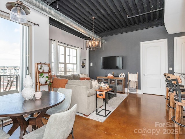 living room featuring an inviting chandelier and concrete flooring