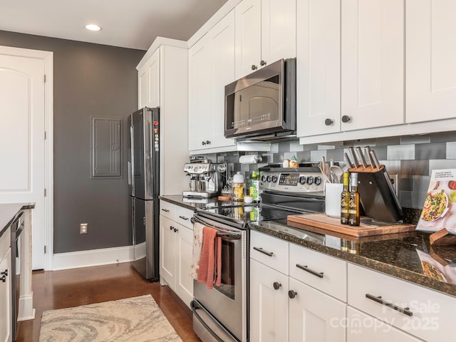 kitchen with white cabinetry, appliances with stainless steel finishes, dark stone counters, and decorative backsplash