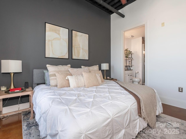 bedroom featuring beam ceiling, ensuite bathroom, baseboards, and wood finished floors