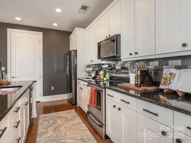 kitchen featuring tasteful backsplash, visible vents, white cabinets, dark stone counters, and stainless steel appliances