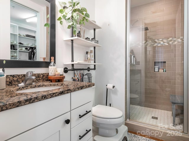 full bathroom featuring a shower stall, toilet, and vanity