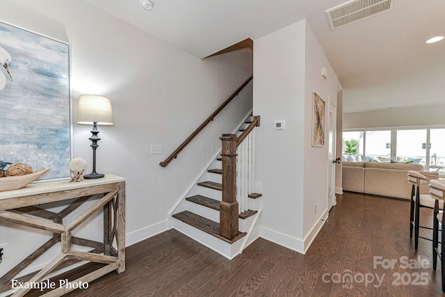 staircase with visible vents, baseboards, and wood finished floors