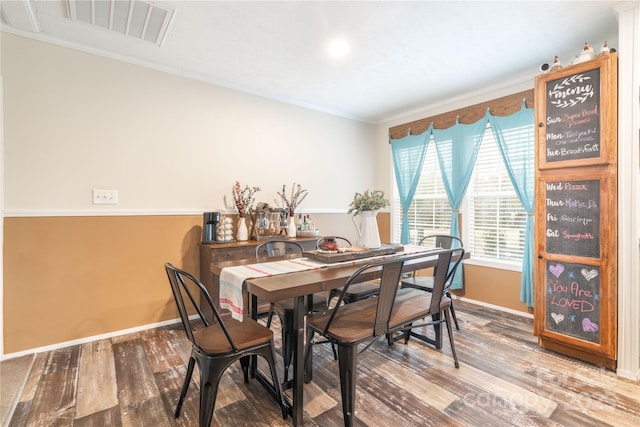 dining space featuring baseboards, visible vents, wood finished floors, and ornamental molding