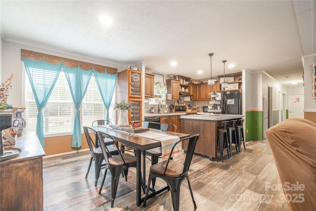 dining area featuring light wood-type flooring, baseboards, crown molding, and recessed lighting