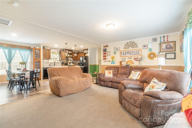 living area with light carpet, visible vents, crown molding, and recessed lighting