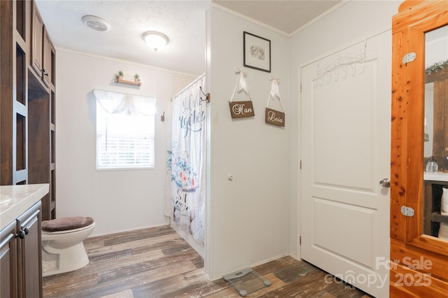 full bathroom featuring a shower with shower curtain, toilet, ornamental molding, vanity, and wood finished floors