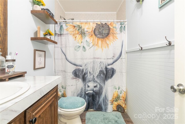 bathroom with a shower with shower curtain, vanity, toilet, and crown molding