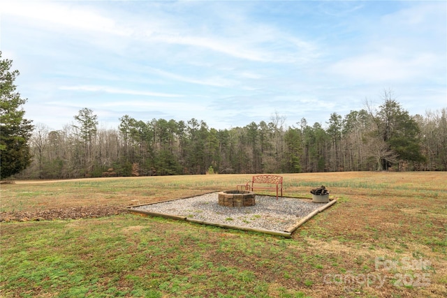 view of yard with a forest view and an outdoor fire pit