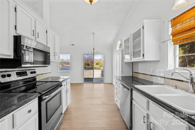 kitchen featuring light wood-style flooring, a sink, white cabinetry, appliances with stainless steel finishes, and pendant lighting