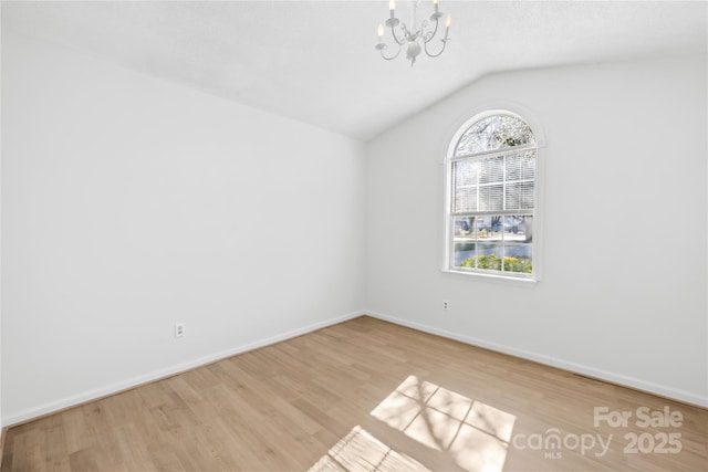 unfurnished room with a notable chandelier, baseboards, vaulted ceiling, and wood finished floors