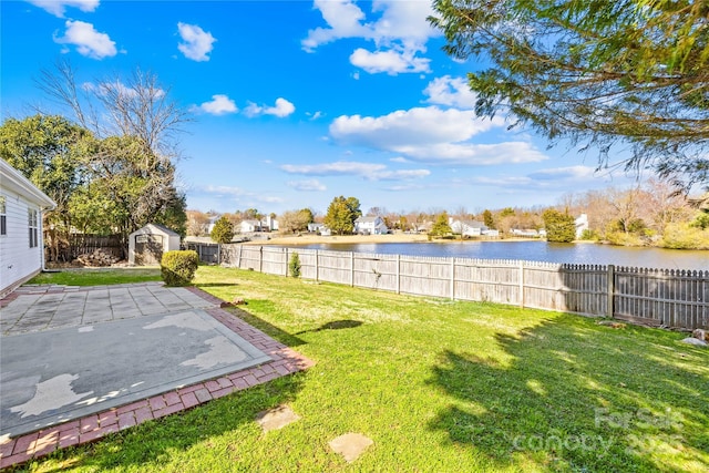 view of yard with an outbuilding, a water view, a storage shed, a patio area, and a fenced backyard