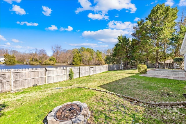 view of yard featuring a patio, an outdoor fire pit, a water view, and a fenced backyard