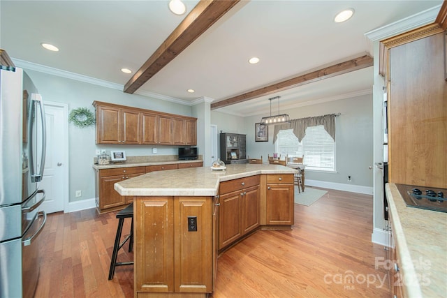 kitchen featuring brown cabinetry, a center island, freestanding refrigerator, light countertops, and beam ceiling