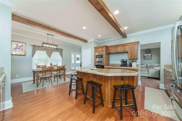 kitchen with light wood finished floors, stainless steel appliances, beamed ceiling, and light countertops