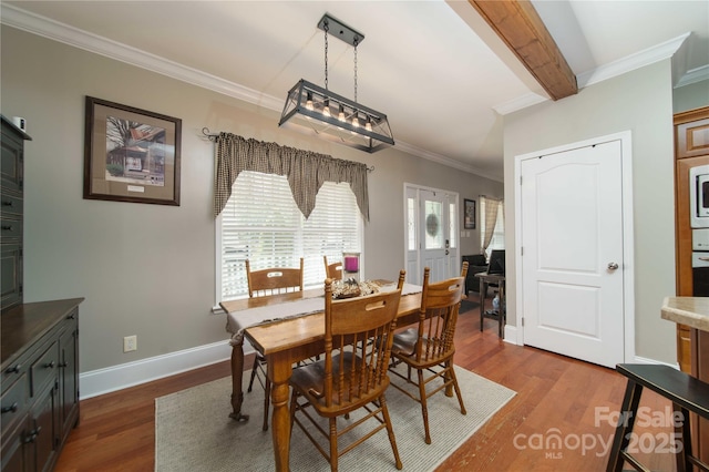 dining room featuring baseboards, ornamental molding, dark wood finished floors, and beam ceiling