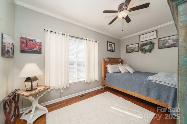 bedroom featuring ceiling fan, wood finished floors, visible vents, baseboards, and ornamental molding