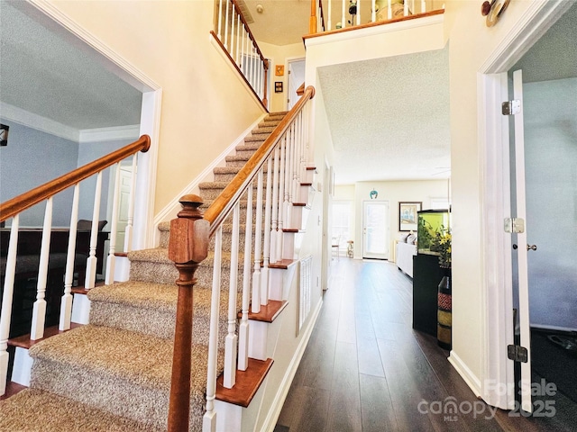 stairway featuring a textured ceiling, wood finished floors, and visible vents