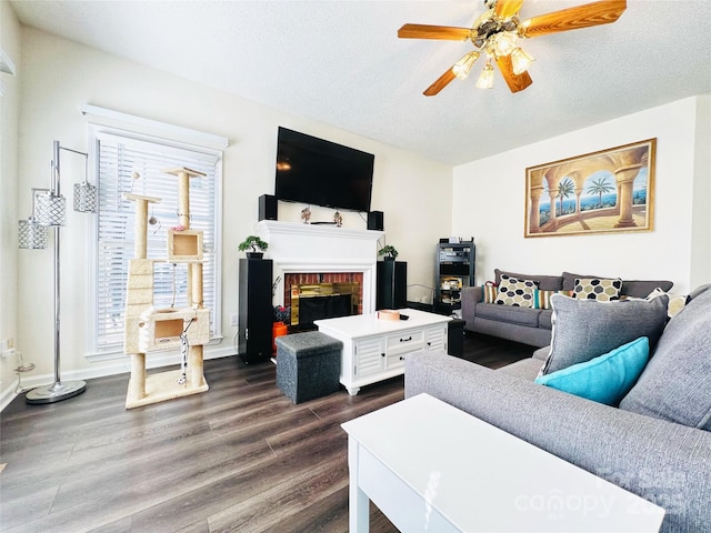 living room featuring baseboards, ceiling fan, dark wood-style flooring, a textured ceiling, and a fireplace