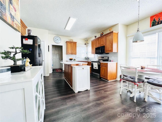 kitchen featuring stainless steel fridge, electric range oven, a center island, light countertops, and black microwave