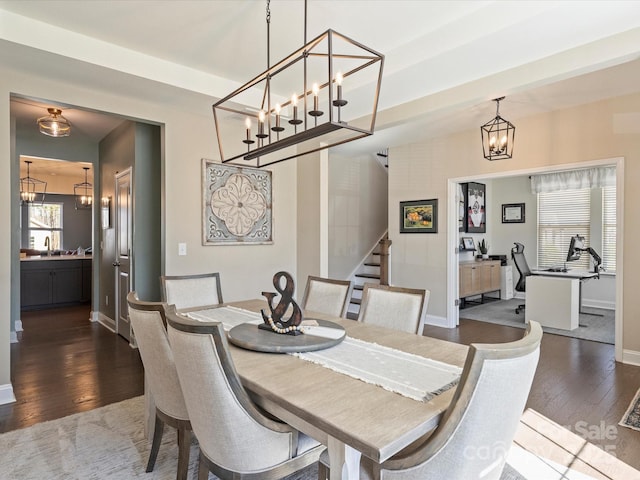 dining room featuring stairway, an inviting chandelier, dark wood-type flooring, and baseboards