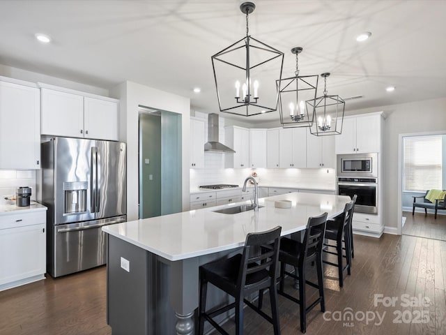 kitchen featuring a sink, white cabinetry, stainless steel appliances, wall chimney exhaust hood, and dark wood-style flooring