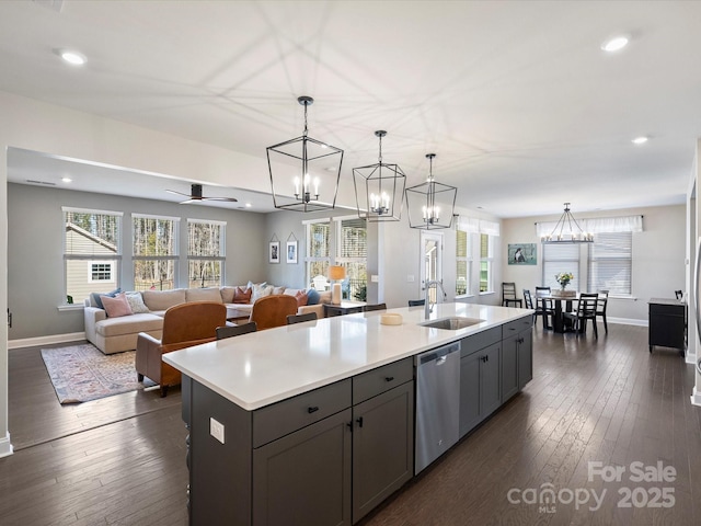 kitchen featuring a kitchen island with sink, a sink, dark wood-style floors, light countertops, and dishwasher