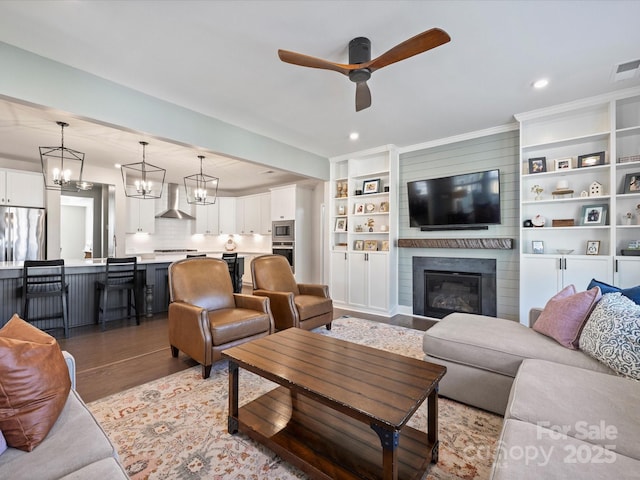 living room with visible vents, light wood-style flooring, recessed lighting, a fireplace, and ceiling fan with notable chandelier