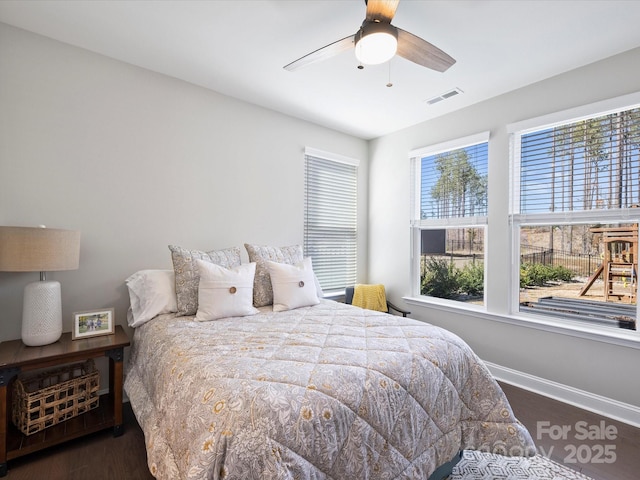 bedroom with a ceiling fan, wood finished floors, visible vents, and baseboards