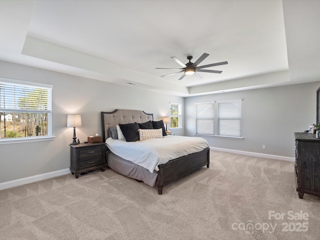 bedroom featuring a tray ceiling, light colored carpet, and baseboards