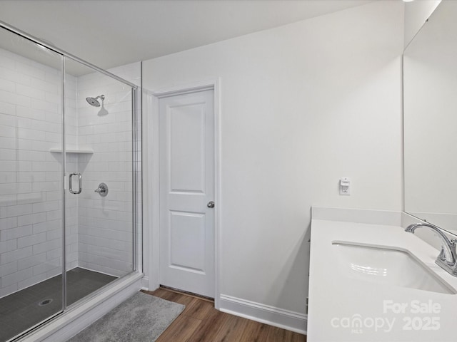 bathroom featuring a shower stall, vanity, baseboards, and wood finished floors
