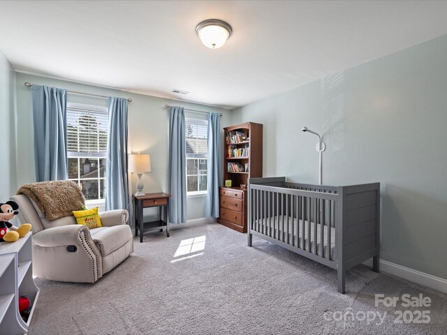 carpeted bedroom featuring a nursery area, multiple windows, baseboards, and visible vents
