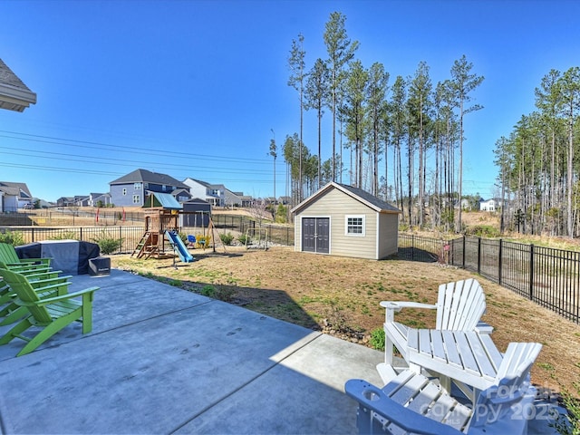 view of yard with an outbuilding, a fenced backyard, a playground, and a patio