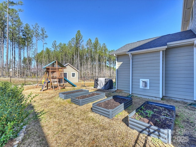 view of yard with a playground, a vegetable garden, and fence