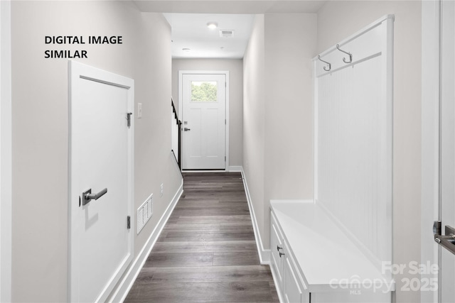 hall featuring dark wood-type flooring, visible vents, and baseboards