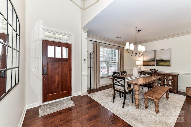 entrance foyer featuring dark wood-style floors, a notable chandelier, baseboards, and ornamental molding