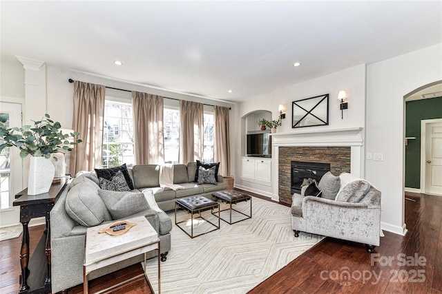 living area with baseboards, recessed lighting, a fireplace, arched walkways, and wood-type flooring