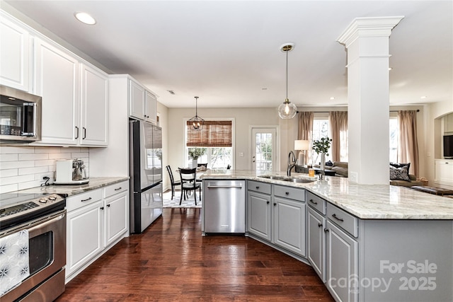 kitchen featuring dark wood-style floors, ornate columns, gray cabinetry, a sink, and appliances with stainless steel finishes