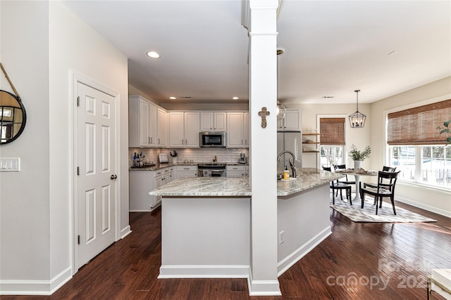 kitchen featuring tasteful backsplash, baseboards, appliances with stainless steel finishes, hanging light fixtures, and dark wood-style flooring