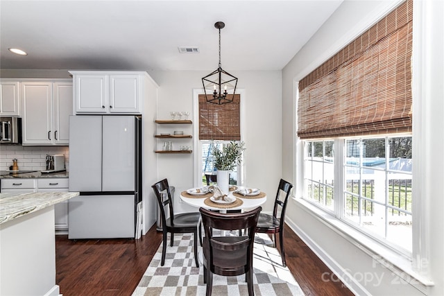 dining room featuring a notable chandelier, visible vents, dark wood-type flooring, and baseboards